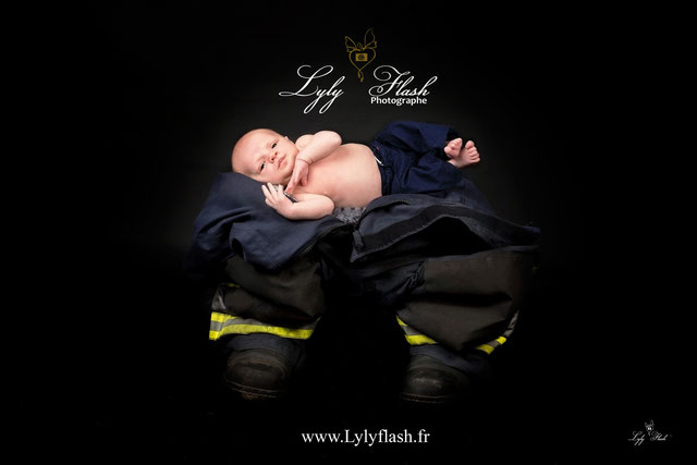 Photo de bébé d'un mois dans l'uniforme de pompier de son papa. Pour expliquer que dans cette famille la passion d'aider son prochain se transmet de père en fils depuis toujours