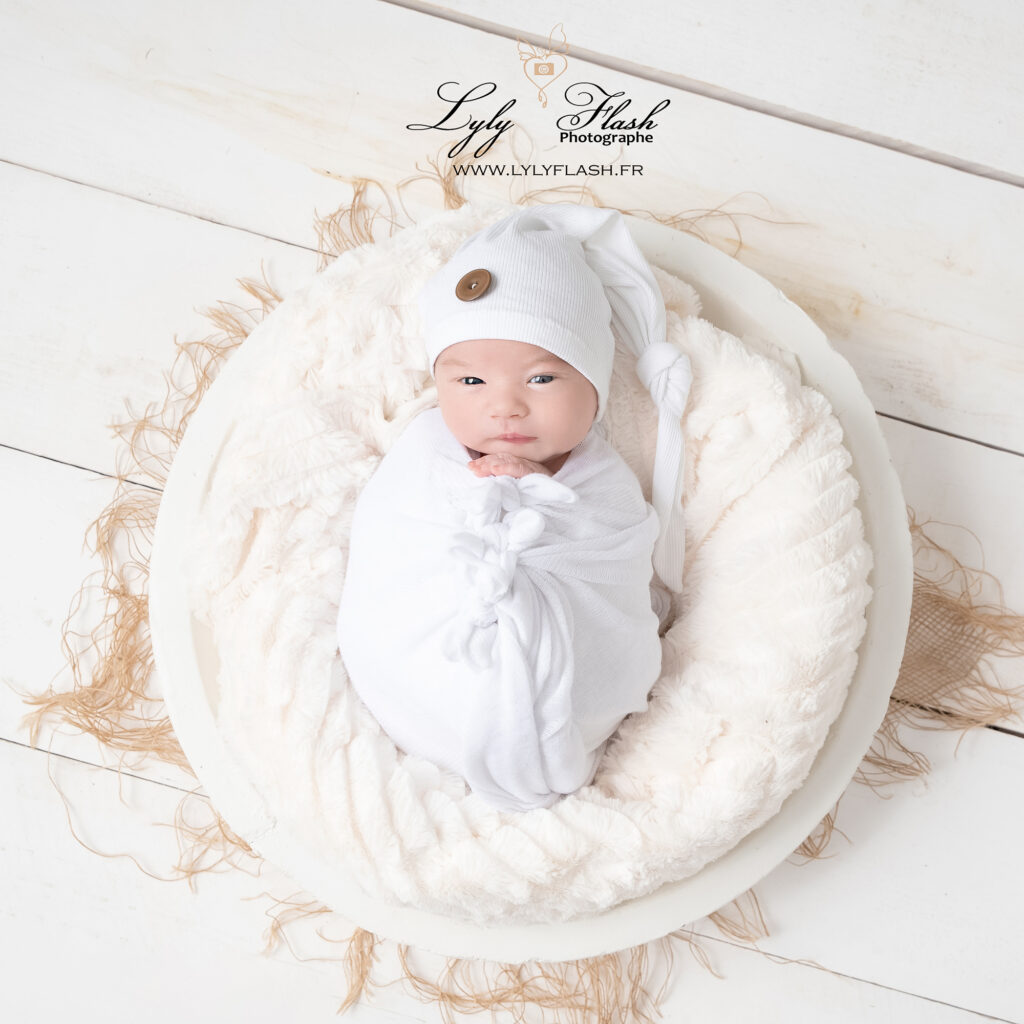 photo naissance, un beau bébé regarde l'objectif de la photographe