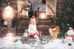 Une magnifique petite fille de 2 ans sur la luge de noël a Cotignac devant la photographe lyly flash