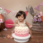 photo d une petite fille pendant son shooting smash the cake qui déguste son magnifique gâteau d'anniversaire