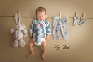 Photographie créative un petit bébé sèche sur une corde a linge avec son doudou et ses vetements