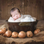 photo de naissance d'un beau bébé qui dort dans une bassine en fer, dans un décor neutre et en même temps créatif.