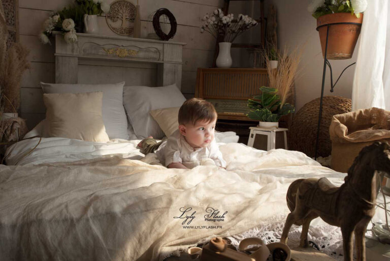 bébé sur le lit d'une maison à la lumiere enveloppante photographe à domicile