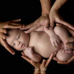 le plus beau bébé métisse pose dans les mains de sa maman son papa et ses deux grandes sœurs, un souvenir tellement mignon, avec ses joues à bisous, une photographie réalisée près de Brignoles au studio photo de la photographe Lyly Flash