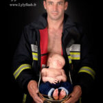 un bébé fraichement venue au monde dort dans le casque de pompier de son papa, une séance photo pour valoriser le métier de pompier et l'implication familiale que celui ci demande. photographie réalise au studio près de Fréjus par la photographe Lyly Flash