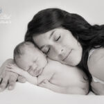 Maman et bébé pose pour une magnifique photographie de naissance, le nouveau-né en position fœtal se met naturellement sur la main de sa maman, Une photographie pleine de douceur et de bienveillance, réalisée pour une famille de Les Arcs