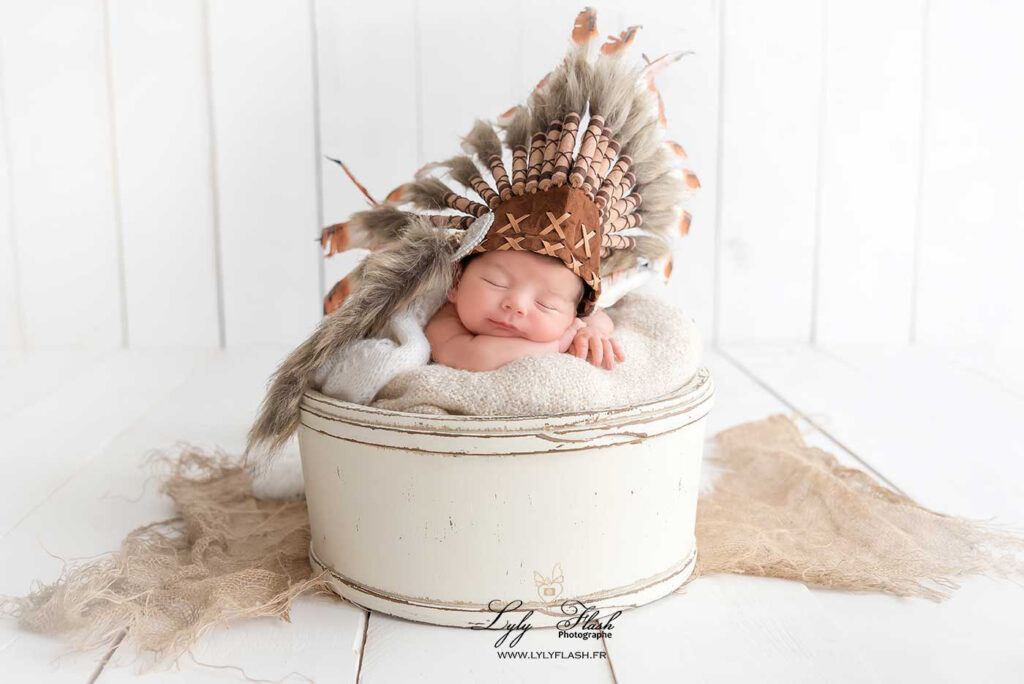 Un beau bébé dort avec une toque d'indien, il est juste sublime et mignon, photographie réalisée pour une famille de Gap par la photographe LylyFLash