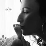 Une photo studio réalisée dans le home studio pour faire comme à la maison. La jeune maman embrasse le pied de sa petite fille. La scène est éclairée en contre jour. Un moment de bonheur pour cette famille de Toulon