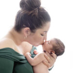 photo de naissance Le bisous de maman, une photographie qui met en valeur la jeune maman en robe verte embrassant son fils pour célébrer sa naissance photographie réalisée en lumière naturel et flash au studio photo de le val