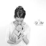 un nouveau-né recoit un bisous de sa maman sur la tête, une photographie de naissance noir et blanc réalisée au studio près de Callian chez Lyly Flash photographe naissance