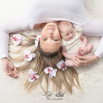 photo d'une jeune maman avec son bébé a la naissance. Des fleurs de tiarés sont dans ses cheveux pour mettre en valeur la féminité et sa petite fille, photographe près de Le Bourget