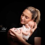 photo de naissance d' un petite fille dans les bras de sa maman, la famille venue de Nice pour ce shooting nouveau-né, déborde de douceur et d'amour, montrant un bébé de 5 jours tout serein et tout sourire