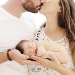 photo de naissance bébé dans les mains des parents qui s'embrasse pour l'arrivée de leur petite fille tout juste naît à Sanary sur Mer