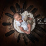 Un beau bébé de Miramas pose dans un thème nature sauvage au studio photo de la photographe, avec ce nid d'oiseau dans lequel il se repose, les plumes noirs autour qui mettent en valeur les traites déjà très masculin de ce nourrisson