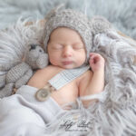 Un beau bébé de Briançon en séance photo naissance dans le studio photo de Lyly flash, une atmosphère douce et cosy, avec cette lumière diffuse, ce petit bonnet gris assorti au doudou qui met en valeur la pureté de ce petit garçon de quelques jours