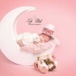 photo de naissance tout en rose avec ce beau bébé au chapeau haut de forme rose, la lune en bois met en valeur la délicatesse de cette petit fille, venue de la garde pour son shooting avec la photographe pro Lyly Flash