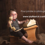 Un beau bébé joue au secrétaire pour le studio photo Lyly flash. C'est trop mignon de le voir porter des lunette rouge et de tendre le combiné du téléphone des année 80, pour vous proposer de contacter la photographe. Une photographie super mignonne pour inciter a contacter la photographe du studio