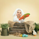 photo portrait d un bébé de 12 mois pour célébrer pâques au studio photo. Il est trop mignon avec sa tenue de petit lapin blanc et son grand sourire qui met en valeur ses deux petits dents de lait