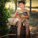 Un petit garçon en pleine nature avec une poule, un portrait plein d'motion et de fierté réalisée dans les jardin de la photographe près de Fréjus