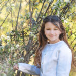 Une belle demoiselle de 6 ans en shooting extérieur avec ses grands cheveux brun et ses yeux dorés