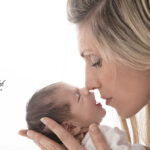 photo de naissance d'une maman nez à nez avec son nourrisson, le nourrisson esquisse un sourire de bonheur de ce câlin. Un moment de tendresse capturé par la rapidité et la capacité d'anticipation de la photographe