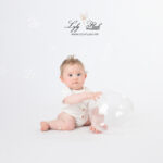 photo bébé en studio intemporelle et naturelle. Le bébé pose dans une tenue blanche avec une bulle de savon géante. Une photographie super Cute réalisée par la photographe Lyly Flash en studio