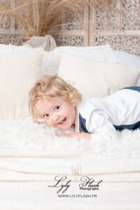 photo bébé 2 ans qui rigole sur le lit. Un souvenir très naturel de ce petit garçon plein de vie par la photographe lyly flash