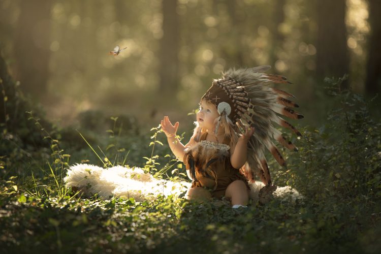 Petite fille dans la foret qui croise un petit papillon. Elle porte une tunique d indienne et une grande toque près de Cabasse